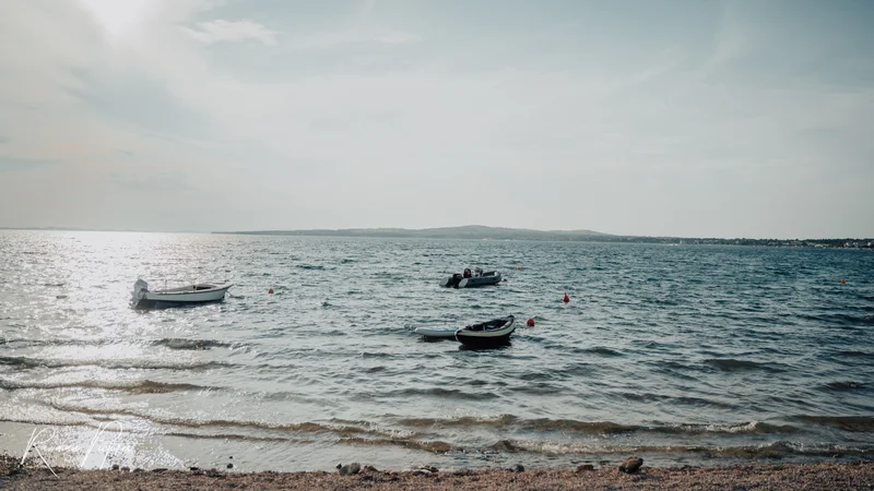 RawmanPictures - Sebastian Schiefermayr | Maturareise Kroatien | Ruhige Küstenfotografie mit Booten und sanften Wellen im Sonnenlicht. Perfekt für entspannte Momente.