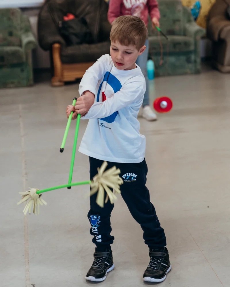 RawmanPictures - Sebastian Schiefermayr | Jonglierworkshop Marchtrenk | Kind spielt drinnen mit Jonglierstöcken, kreative Kinderfotografie.