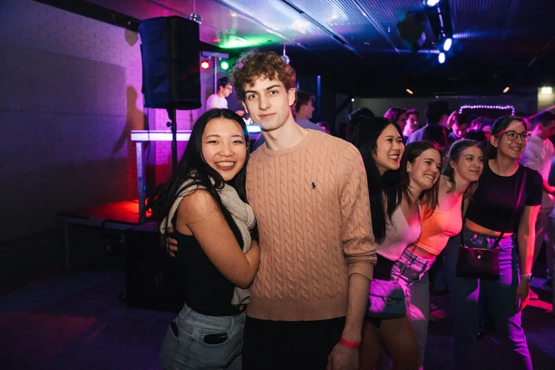 RawmanPictures - Sebastian Schiefermayr | JKU Mensafest | Jugendliche feiern in stimmungsvoller Club-Atmosphäre mit bunten Lichtern und lebhaften Gesichtern.
