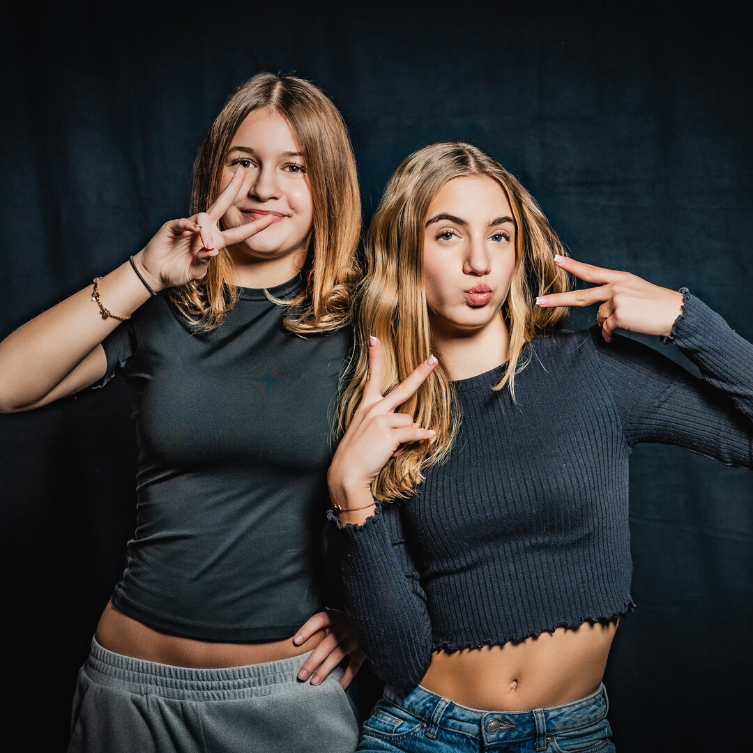 RawmanPictures - Sebastian Schiefermayr | Portrait-Shooting Ozon | Zusammenfassung: Zwei junge Frauen posieren fröhlich vor einem dunklen Hintergrund im Studio.