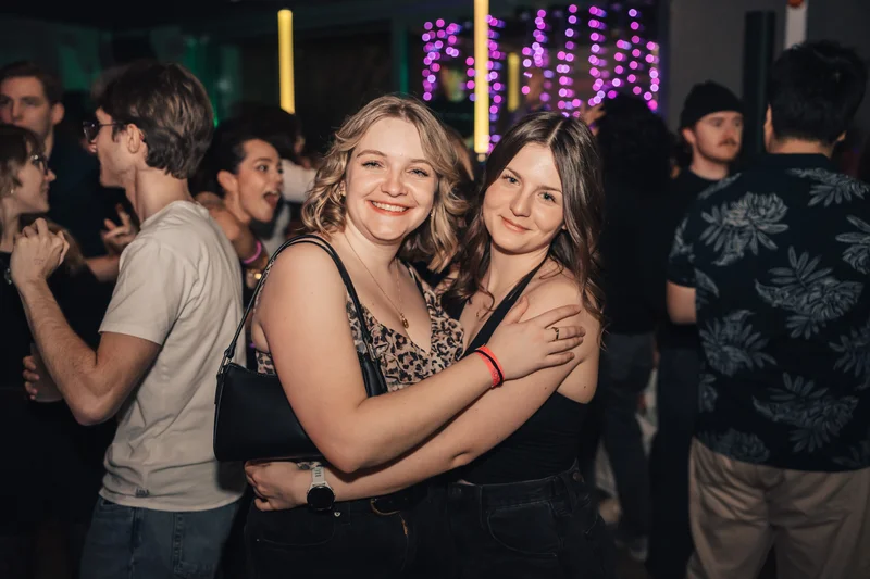 RawmanPictures - Sebastian Schiefermayr | JKU Mensafest | Zwei Freundinnen lächeln bei einer Party in die Kamera. Eventfotografie, Nachtleben, Spaß.