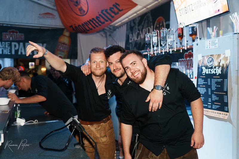 RawmanPictures - Sebastian Schiefermayr | Stadtfest-Marchtrenk  | Barpersonal in Lederhosen serviert Getränke an gut besuchter Bar. Eventfotografie, Partyatmosphäre.