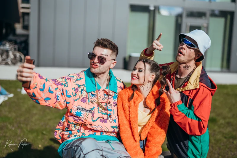 RawmanPictures - Sebastian Schiefermayr | Musikvideodreh "Flinz Asozial" | 80s-Stil Outdoor-Porträtfotografie, Gruppe in bunten Retro-Outfits beim Selfie.