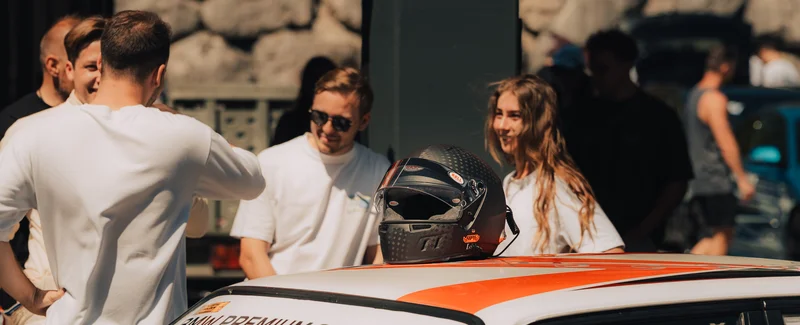 RawmanPictures - Sebastian Schiefermayr | Motortag 2026 | Junge Menschen im Gespräch bei einem Motorsport-Event, Helmkameradschaft im Vordergrund.