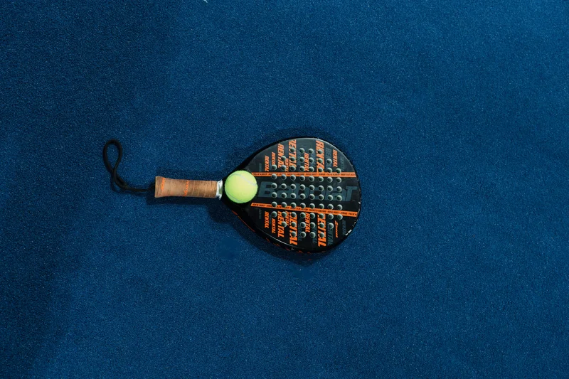RawmanPictures - Sebastian Schiefermayr | Padelbase Videodreh | Padelschläger auf blauem Boden für dynamischen Sportfotografie-Stil.