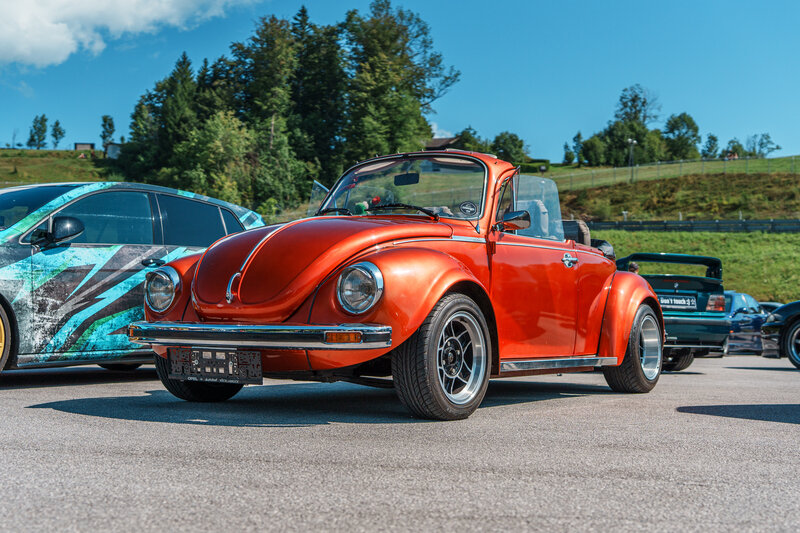 RawmanPictures - Sebastian Schiefermayr | Motortag 2026 | Klassischer roter VW Käfer Cabrio auf Sommerstraße, Oldtimer, Vintage Autotreffen, sonniger Tag.