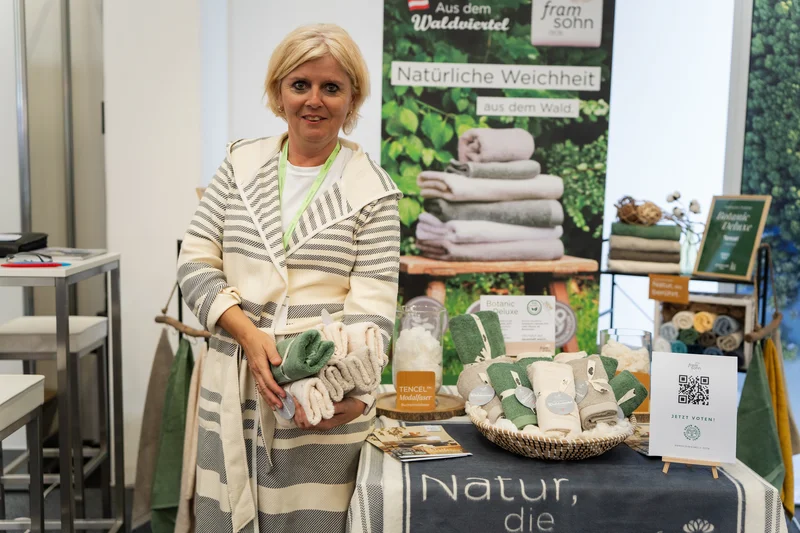 RawmanPictures - Sebastian Schiefermayr | Marke[ding] Wels | Frau präsentiert ökologische Handtücher aus dem Waldviertel auf Messestand. Hochwertige Naturprodukte.
