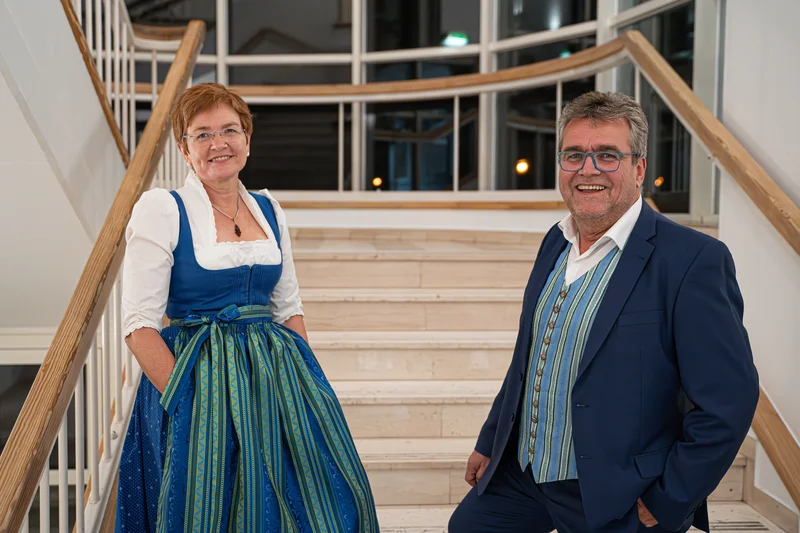 RawmanPictures - Sebastian Schiefermayr | Volkstanzfest | Eine Frau und ein Mann in traditioneller bayerischer Tracht auf einer Treppe.