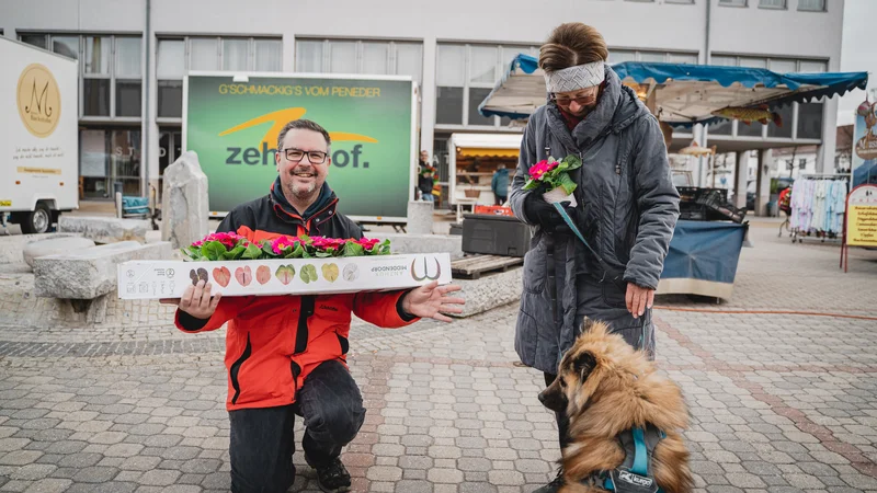 RawmanPictures - Sebastian Schiefermayr | Valentinsaktion Marchtrenk | Outdoor-Markt: Fröhliche Menschen mit Blumen und Hund. Perfekt für Stadtleben-Fotografie.