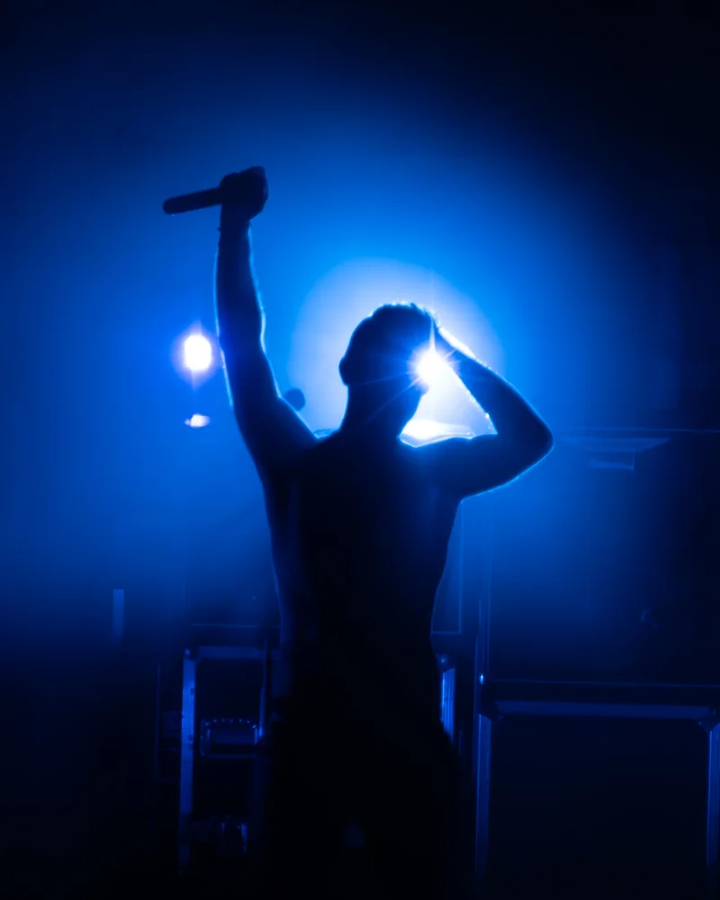 RawmanPictures - Sebastian Schiefermayr | Krampusnacht | Bühnensänger-Silhouette in blauem Scheinwerferlicht, Musikfotografie Highlights.