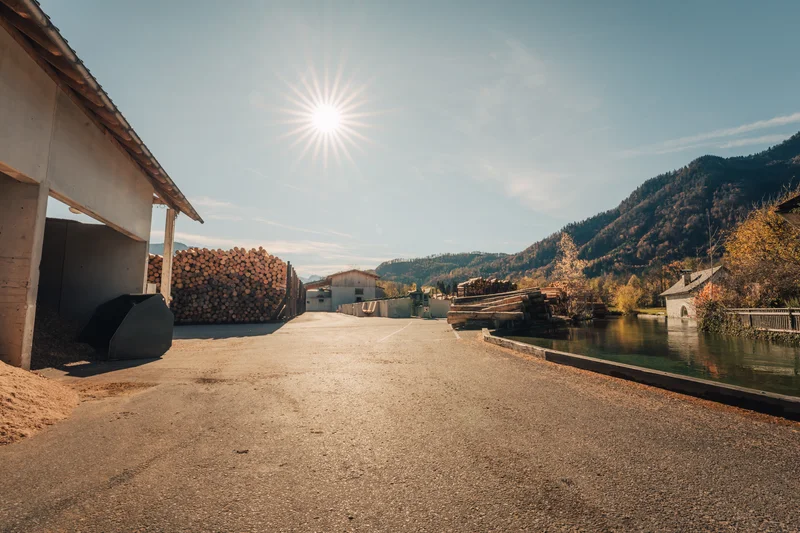 RawmanPictures - Sebastian Schiefermayr | Sägewerk Löberbauer | Sonnenuntergang über Berglandschaft, beeindruckende Outdoor-Fotografie mit Holzlager.