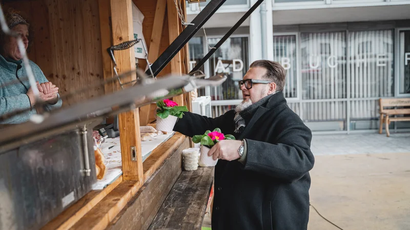 RawmanPictures - Sebastian Schiefermayr | Valentinsaktion Marchtrenk | Besucher kauft Blumen an Marktstand, Stadtleben, Outdoor-Fotografie, bunter Frühlingsmarkt.