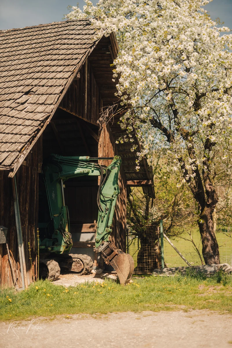 RawmanPictures - Sebastian Schiefermayr | Kirschblüten­wanderung  | Rustikale Scheune und Bagger im Frühling, Landschaftsfotografie, ländliche Idylle.