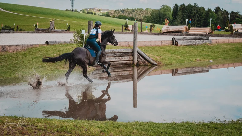 RawmanPictures - Sebastian Schiefermayr | Vielseitigkeits­turnier | Pferdesportfotografie: Eleganter Reiter auf kraftvollem Pferd im Wasserhindernis.
