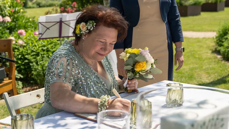 RawmanPictures - Sebastian Schiefermayr | Hochzeit Traude & Gerhard | Hochzeitsfotografie: Glücklicher Moment beim Unterschreiben im Freien, lebendige Blumenarrangements.