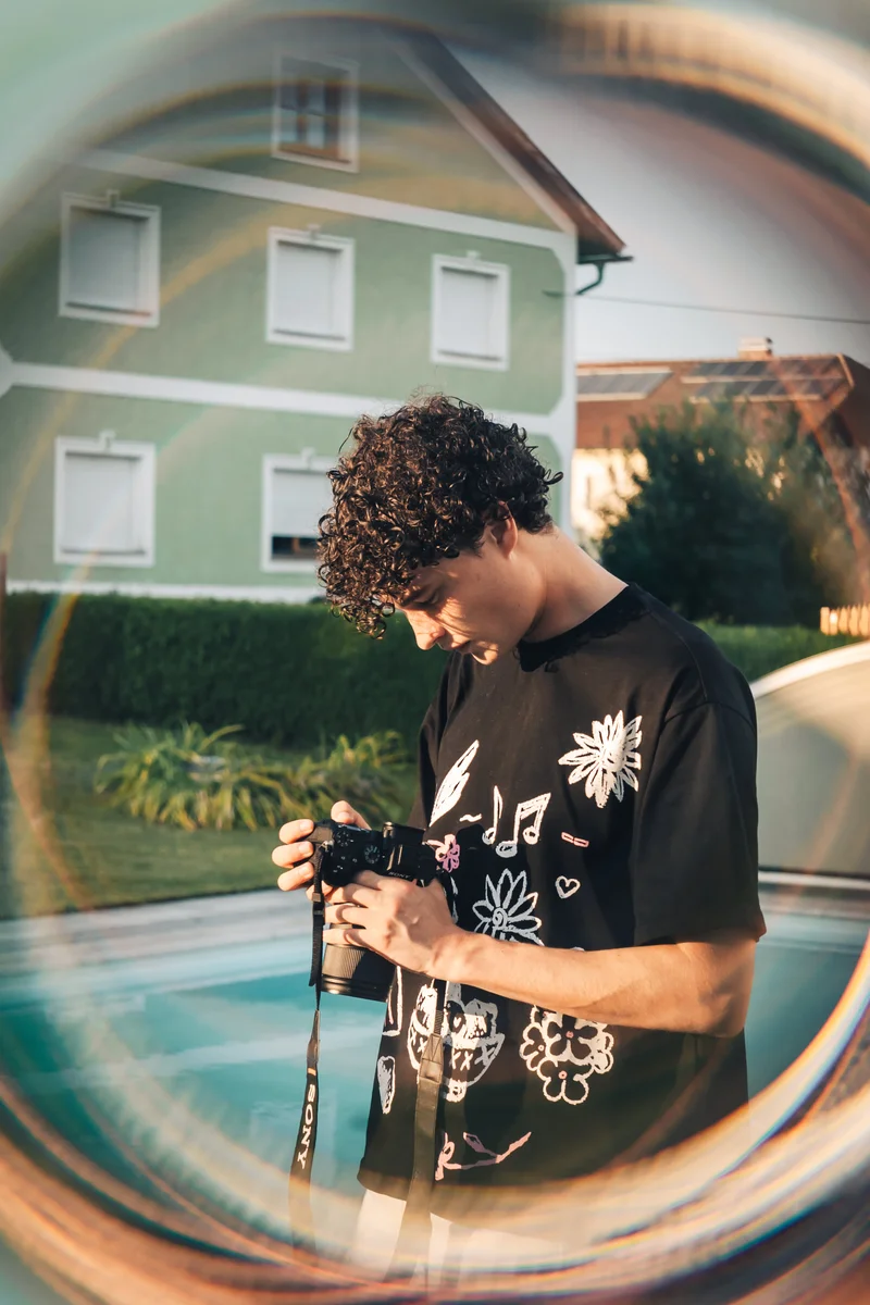 RawmanPictures - Sebastian Schiefermayr | Vality & Friends | Junger Fotograf mit Kamera im Garten, stimmungsvolle Lichtwirkung, kreative Fotografie.