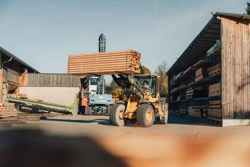 RawmanPictures - Sebastian Schiefermayr | Sägewerk Löberbauer | Gabelstapler transportiert Holzstapel im Hof eines Sägewerks. Industrie- und Lagerfotografie.