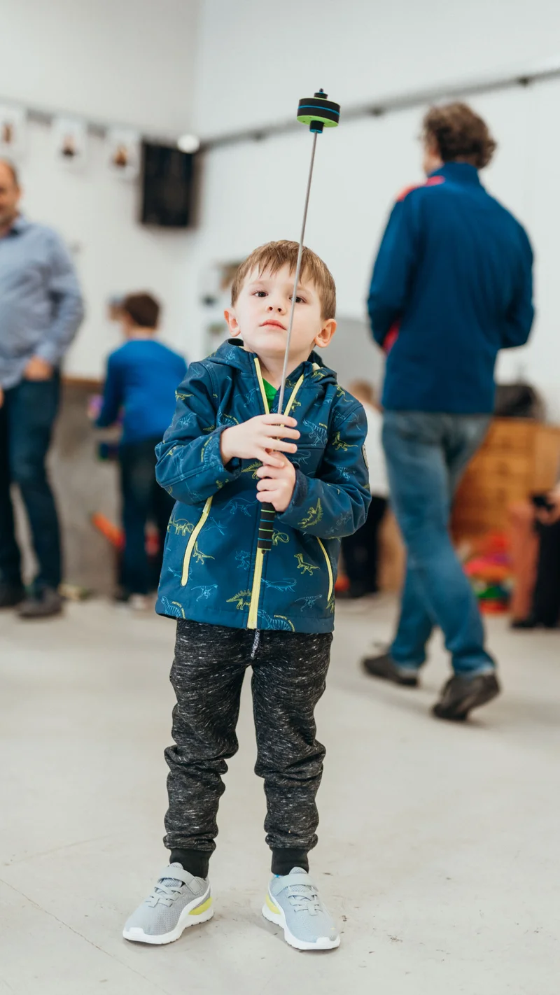 RawmanPictures - Sebastian Schiefermayr | Jonglierworkshop Marchtrenk | Junge spielt konzentriert mit Ball, Kinderfotografie, Indoor-Event, natürliche Momente einfangen.
