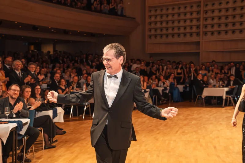 RawmanPictures - Sebastian Schiefermayr | Maturaball HTL1 | Elegant gekleidete Person auf Gala mit Publikum im Hintergrund. Eventfotografie, festliche Atmosphäre.
