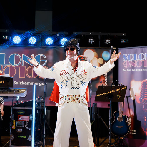 RawmanPictures - Sebastian Schiefermayr | Solong - Charity Event | Bühne Performance Eventfotografie: Musiker in Elvis-Outfit, lebendige Show, Lichter und Instrumente.