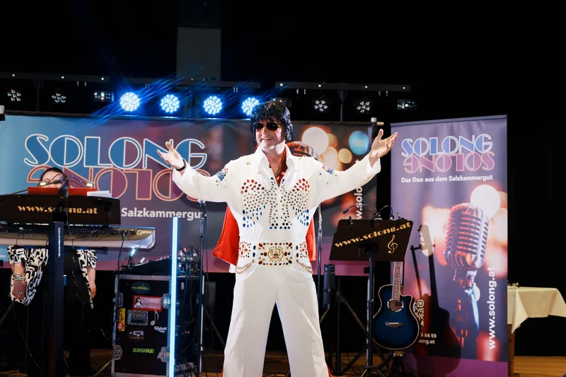 RawmanPictures - Sebastian Schiefermayr | Solong - Charity Event | Bühne Performance Eventfotografie: Musiker in Elvis-Outfit, lebendige Show, Lichter und Instrumente.