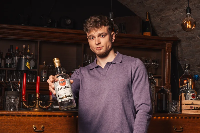 RawmanPictures - Sebastian Schiefermayr | Portraitshooting Kevin F. | Portrait in Bar, junger Mann mit Bacardi-Flasche, stilvolle Szenefotografie.