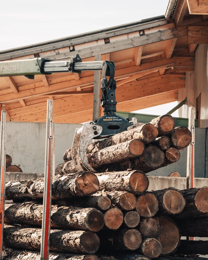 RawmanPictures - Sebastian Schiefermayr | Sägewerk Löberbauer | Holzverarbeitung: Industriekran stapelt Baumstämme im Sägewerk für effiziente Logistiklösungen.