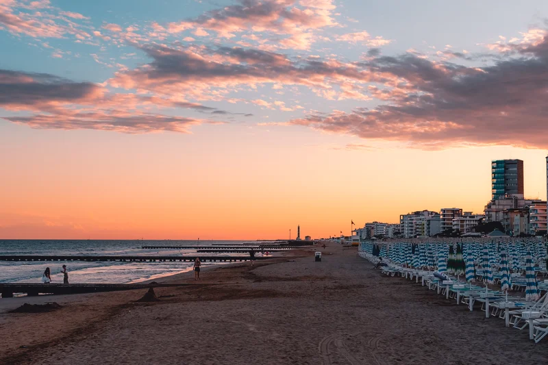 RawmanPictures - Sebastian Schiefermayr | Urlaub Jesolo | Sonnenuntergang am Strand mit Himmel, Gebäuden und Meer; stimmungsvolle Küstenfotografie.