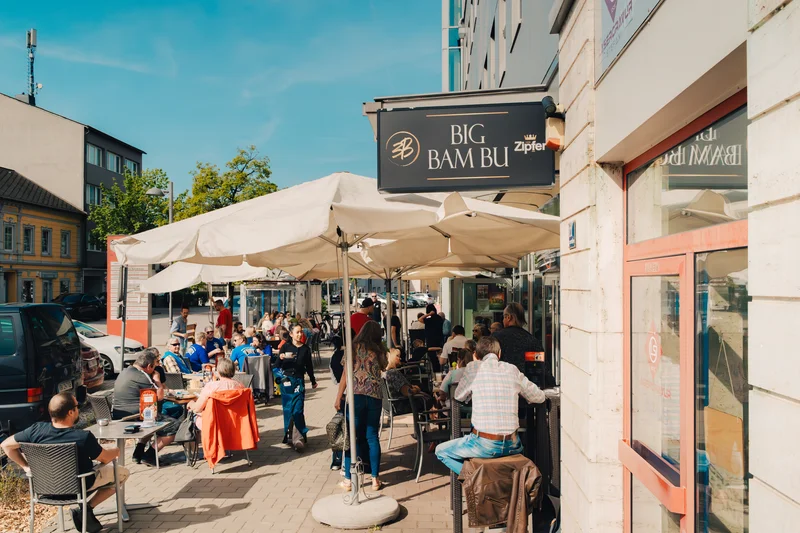 RawmanPictures - Sebastian Schiefermayr | Charity Brunch | Caféstraßenfotografie, sonnige Atmosphäre, lebendige Straßenszene, Outdoor-Gastronomie.