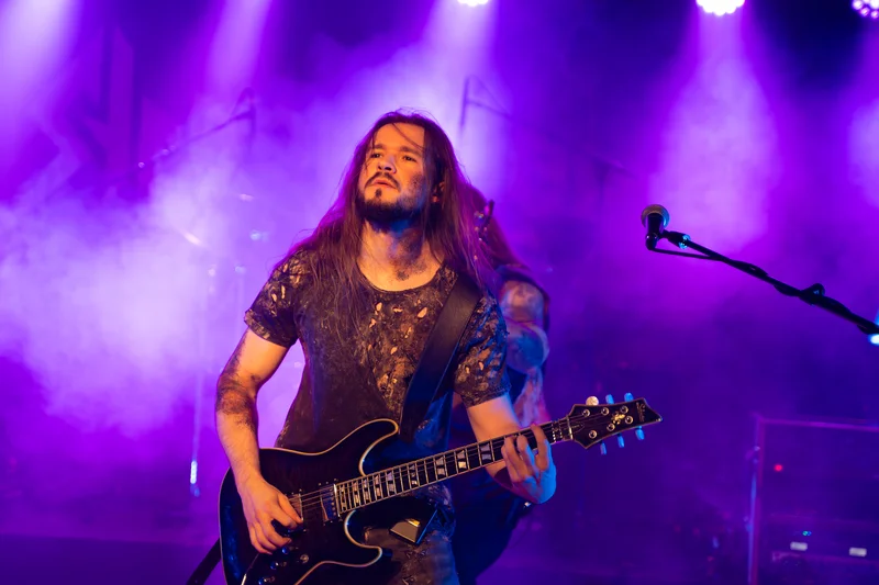 RawmanPictures - Sebastian Schiefermayr | Krampusnacht | Live-Musikfotografie, Gitarrenperformance in lila Bühnenbeleuchtung, Konzertauftritt.