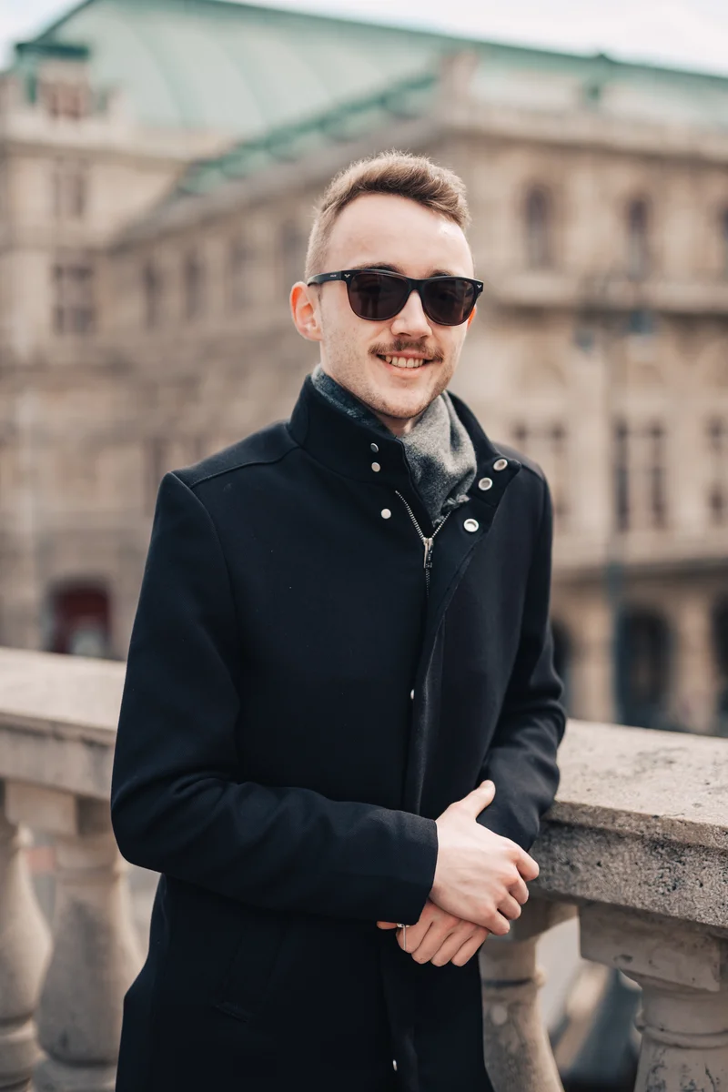 RawmanPictures - Sebastian Schiefermayr | Daytrip Wien | Eleganter Mann in Winterkleidung vor historischer Architektur. Perfekt für Porträtaufnahmen.