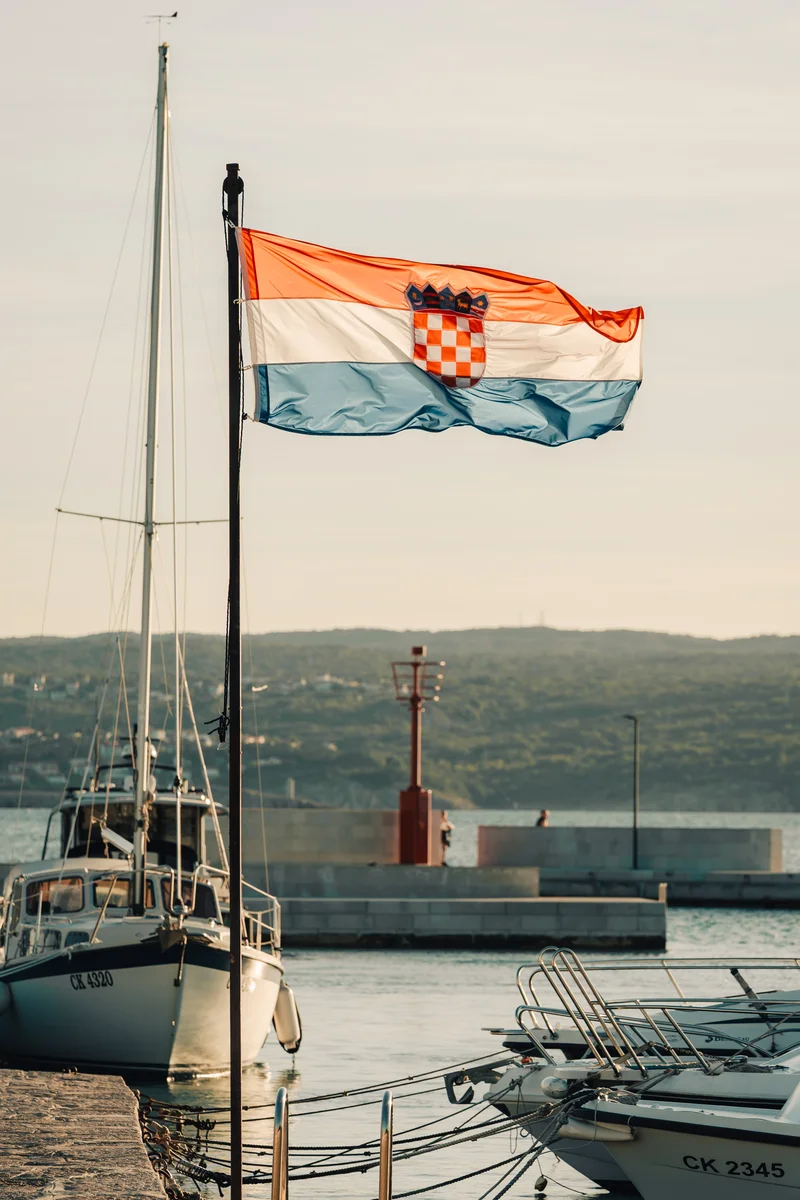 RawmanPictures - Sebastian Schiefermayr | Content Trip: Crikvenica 2025 | Kroatisches Küstenpanorama: Flagge, Boote und malerischer Hafen im Abendlicht.