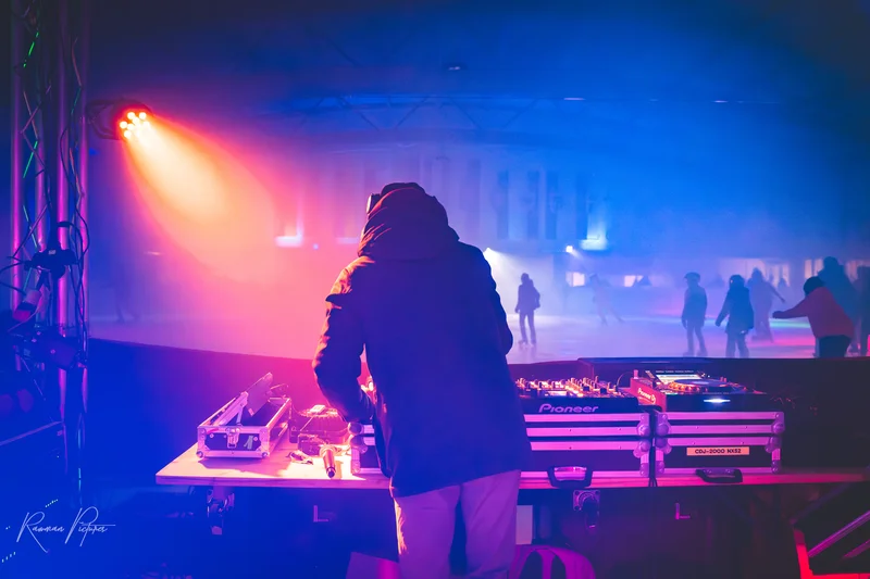 RawmanPictures - Sebastian Schiefermayr | Eisdisco Marchtrenk | DJ bei Party mit bunten Lichtern und tanzender Menge, Eventfotografie, lebendige Atmosphäre.