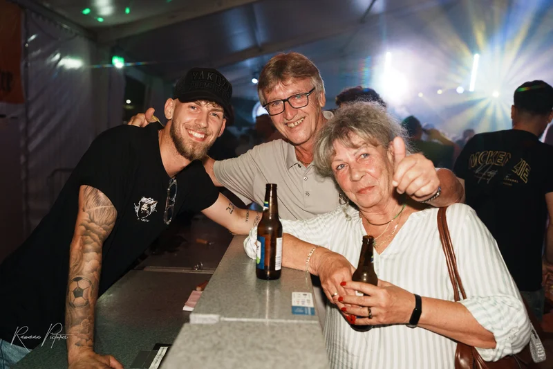 RawmanPictures - Sebastian Schiefermayr | Stadtfest-Marchtrenk  | Menschen feiern in Festzelt-Atmosphäre, lächelnd mit Getränken an der Bar. Eventfotografie.