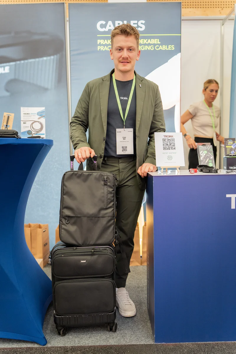 RawmanPictures - Sebastian Schiefermayr | Marke[ding] Wels | Mann auf Messe mit Koffer und Kabelzubehör am Stand. Eventfotografie, Produktpräsentation.
