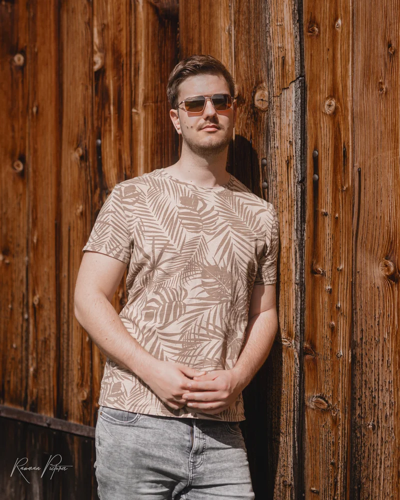 RawmanPictures - Sebastian Schiefermayr | Kirschblüten­wanderung  | Lässig-urbanes Porträtfoto eines Mannes an Holzwand, ideal für Mode- und Lifestyle-Shootings.