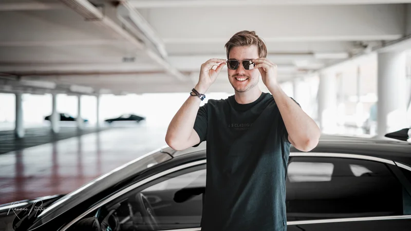 RawmanPictures - Sebastian Schiefermayr | Personal Shooting | Porträt eines jungen Mannes in moderner Parkgarage mit Sonnenbrille und Auto. Fotograf Hamburg.