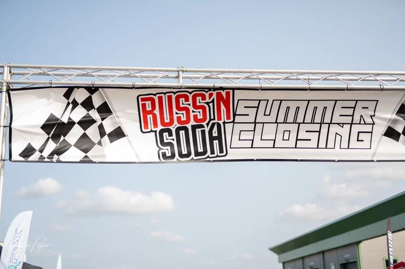 RawmanPictures - Sebastian Schiefermayr | Russnsoda Summer Closing | Banner mit Rennsport-Event-Logo unter freiem Himmel für Fotografie-Präsentation.