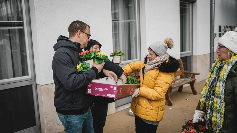 RawmanPictures - Sebastian Schiefermayr | Valentinsaktion Marchtrenk | Menschen verteilen Blumen in winterlicher Kleidung. Gemeinschaft, Freude, Wohltätigkeit.