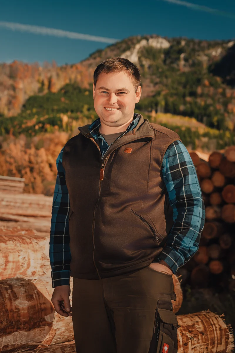 RawmanPictures - Sebastian Schiefermayr | Sägewerk Löberbauer | Outdoor-Porträtfotografie von einem lächelnden Mann in herbstlicher Bergkulisse.