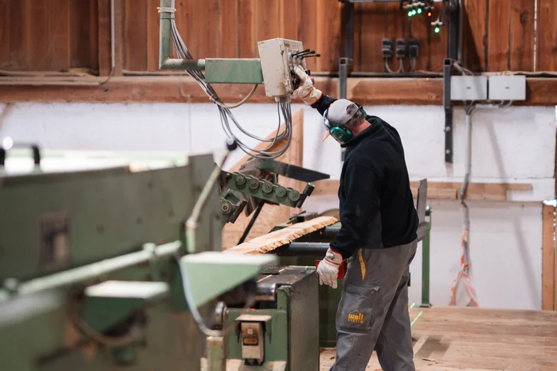 RawmanPictures - Sebastian Schiefermayr | Sägewerk Löberbauer | Arbeiter in Holzbearbeitungswerkstatt; industrielle Holzverarbeitung; präzise Maschinenarbeit.
