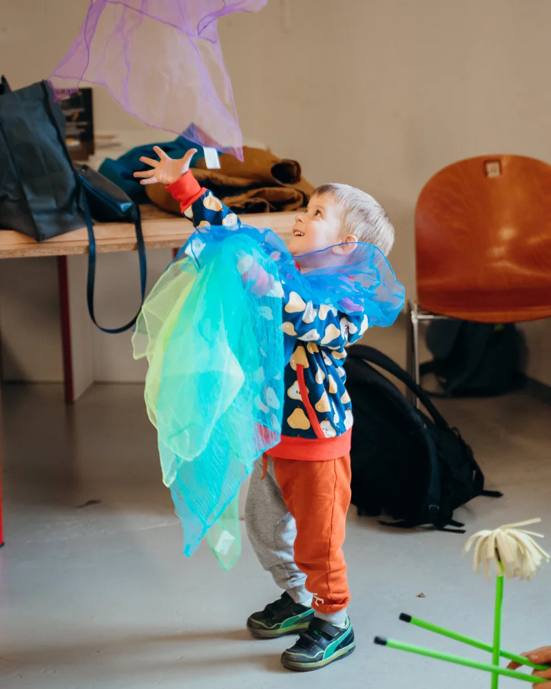 RawmanPictures - Sebastian Schiefermayr | Jonglierworkshop Marchtrenk | Kinderfotografie: Spielender Junge mit bunten Tüchern in kreativer Atmosphäre indoorshooting.