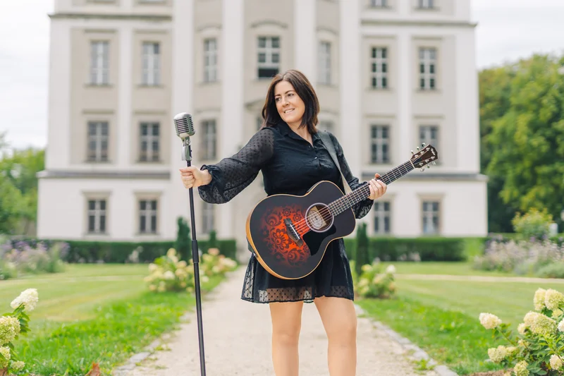 RawmanPictures - Sebastian Schiefermayr | Portraitshooting Tamara R. | Frau mit Gitarre vor Schloss, Musikfotografie im Freien. Vintage Mikrofon, kreative Porträts.