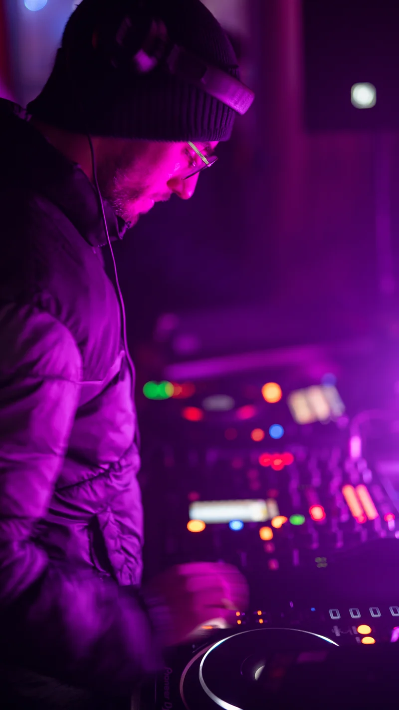 RawmanPictures - Sebastian Schiefermayr | Eisdisco Marchtrenk | DJ in Aktion vor Mischpult, lila Beleuchtung, Nachtclub Atmosphäre, Eventfotografie.
