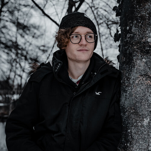 RawmanPictures - Sebastian Schiefermayr | Wintershooting Maximilian W. | Portrait im Winterwald, Mann mit Brille, warme Kleidung, Fotografie im Freien.
