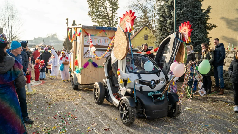RawmanPictures - Sebastian Schiefermayr | Faschingsumzug Weißkirchen | Farbenfroher Karnevalsumzug mit geschmücktem Wagen und fröhlichen Zuschauern auf der Straße.