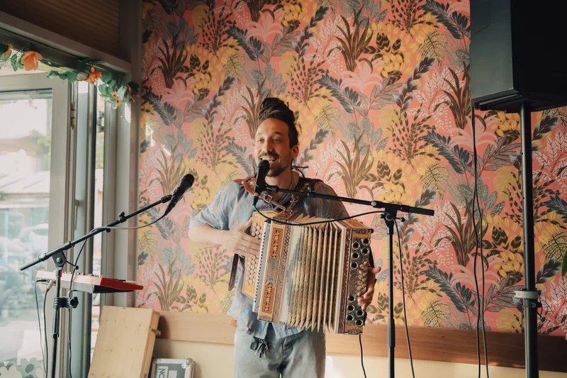 RawmanPictures - Sebastian Schiefermayr | Charity Brunch | Musiker mit Akkordeon im gemütlichen Café. Live-Musik Fotografie für kreative Momente.