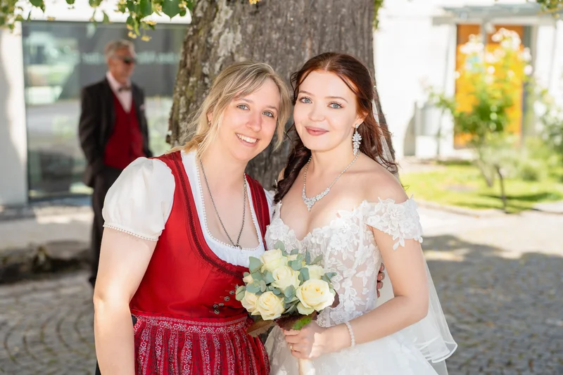 RawmanPictures - Sebastian Schiefermayr | Hochzeit Natalia & Jürgen | Fröhliche Hochzeitsmomente: Braut und Gäste in traditioneller Tracht unter Bäumen.