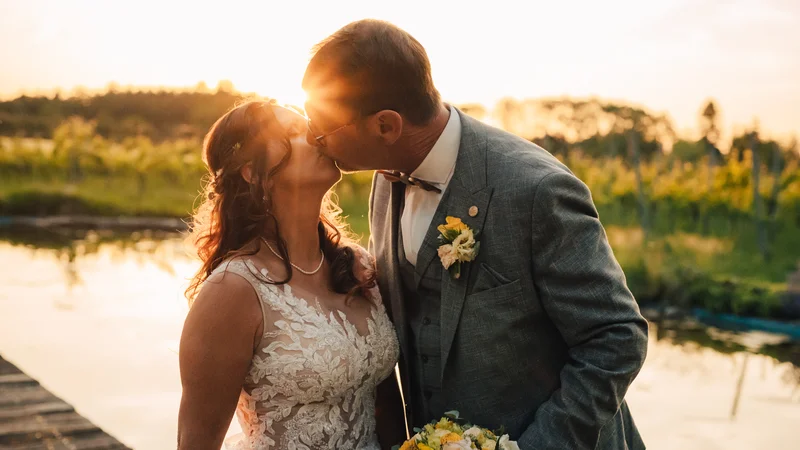 RawmanPictures - Sebastian Schiefermayr | Hochzeit Traude & Gerhard | Romantische Hochzeitsfotografie bei Sonnenuntergang am See, Brautpaar küsst sich.
